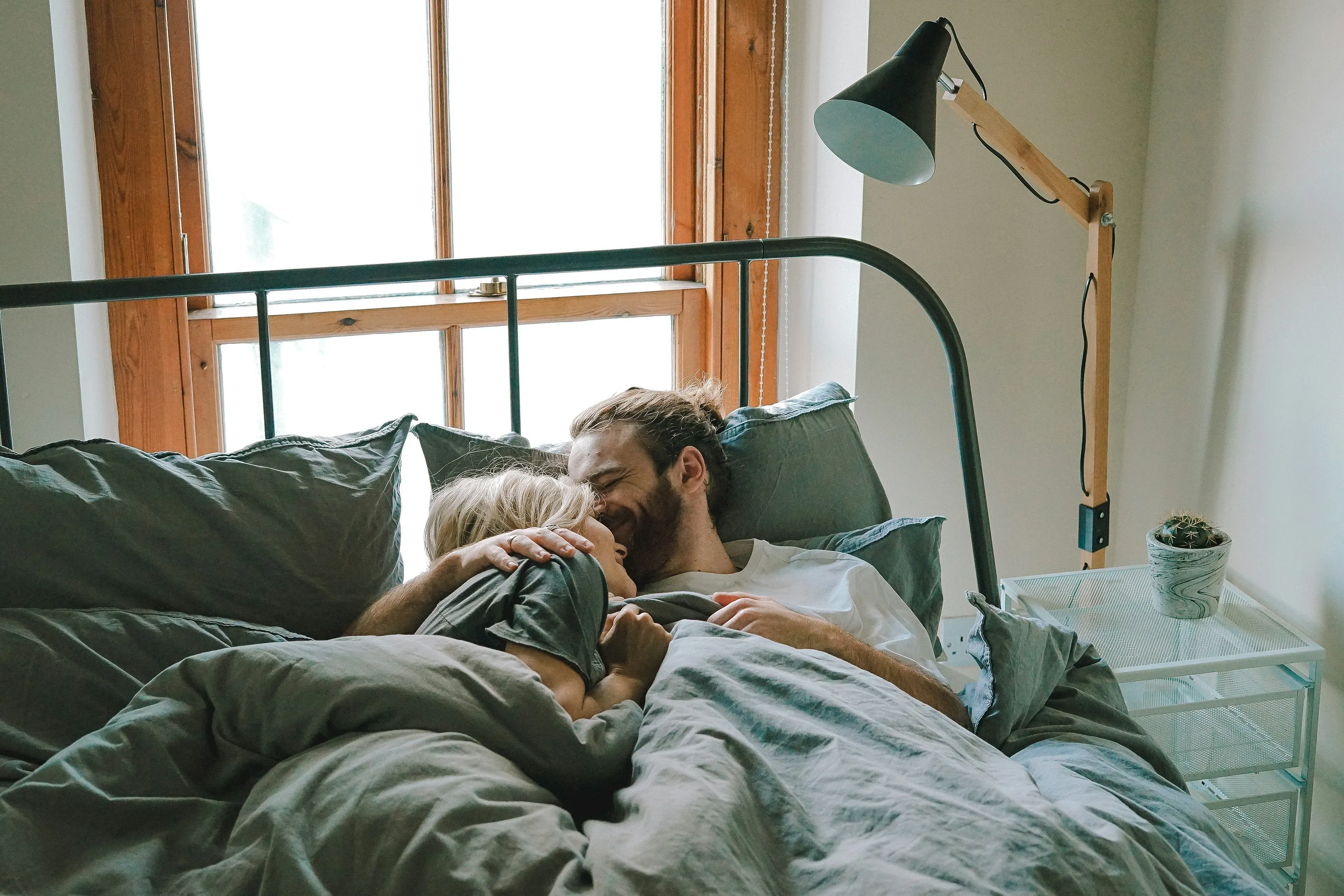 Man and woman kissing and cuddling in bed